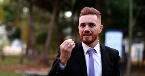 Angry business man standing arguing to camera outside. Upset executive in argument