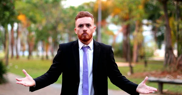 Angry business man standing arguing to camera outside. Upset executive in argument