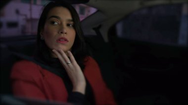 Endişeli bir kişi arabanın arka koltuğunda trafiğe takılmış. Genç bir kadın gece işten sonra aracın içinde kaygı duyuyor.