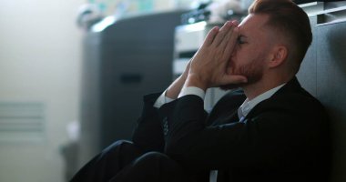 İş adamı evde oturup hayal kırıklığı ve endişe hissediyor.