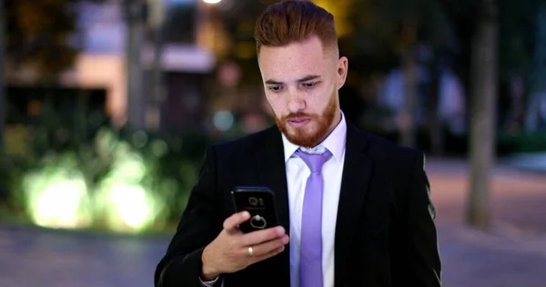ビジネスマンは夜に携帯電話を見て歩く 夜間にスマートフォンを携帯する執行役 — ストック写真