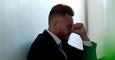 Hüsrana uğramış iş adamı yerde oturup umutsuzluk hissediyor.