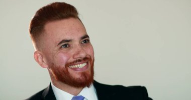 Mutlu adam gülümsüyor. İyi haberler aldığında seviniyor. Hoş sürpriz bir gülümseme, takım elbiseli kızıl saçlı adam.