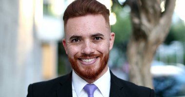 Yakışıklı yönetici kameraya gülümsüyor, İrlandalı kızıl saçlı erkek dışarıda bekliyor.