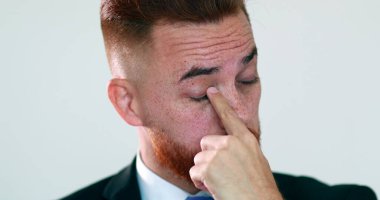 Dalgın bir adam elleriyle yüzüne dokunuyor. Düşünen iş adamı parmaklarıyla gözünü ovalıyor.