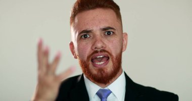 Elleriyle hareket eden ve kamerayla konuşan üzgün iş adamı.