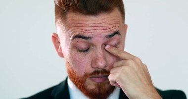 Pensive man touching face with hand. Thinking business person rubbing eye with finger