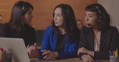 Bayan yönetici bilgisayar dizüstü bilgisayarının önünde personele veri sunuyor. Kadın çalışanlar, kadın liderleri dinliyorlar.