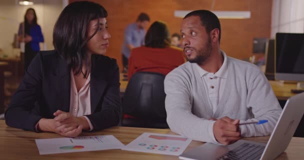 两个千禧年的员工站在笔记本电脑前一位黑人同事解释了一位南美女雇员的新工作 新工作概念的第一天 — 图库视频影像