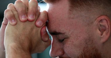 Genç adam meditasyon ve tefekküre dalmış umutla ve inançla bakıyor.