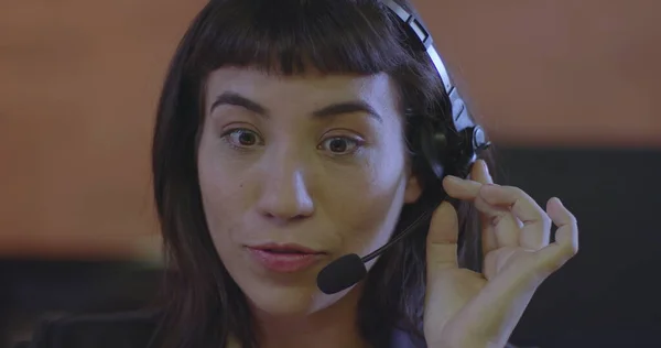 Business woman speaking with headset. Portrait face closeup of young woman talking with client on microphone. One female hispanic telemarketer speaking on headset with customer