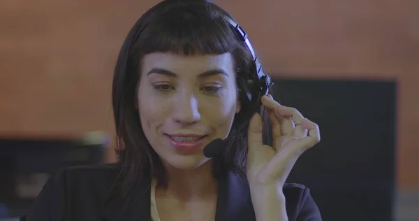 Business woman speaking with headset. Portrait face closeup of young woman talking with client on microphone. One female hispanic telemarketer speaking on headset with customer