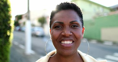 Güzel Afrikalı kadın kameraya gülümsüyor. Açık havada mercekli mutlu siyah ırk kadını.