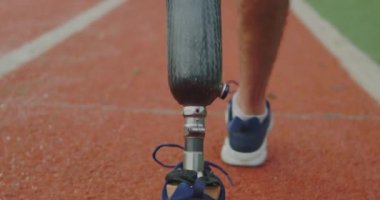 Man with prosthetic leg walking outside. Closeup of disabled Athlete. Amputee training on outdoor park stadium