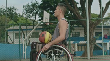 Dışarıda basketbol sahasında tekerlekli sandalyedeki felçli bir basketbolcu. Engelli sporu ve sakatlık konsepti