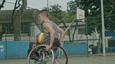 Dışarıda basketbol sahasında tekerlekli sandalyedeki felçli bir basketbolcu. Engelli sporu ve sakatlık konsepti