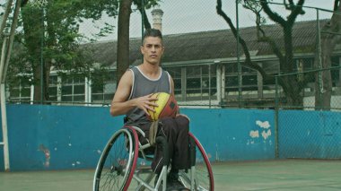 Sahada top oynayan İspanyol engelli bir basketbolcunun portresi. Belden aşağısı felçli bir sporcu kameraya bakıyor.