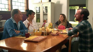 Family sitting at breakfast table in the morning. Older parents with adult son and daughter together