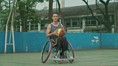 Sahada top oynayan İspanyol engelli bir basketbolcunun portresi. Belden aşağısı felçli bir sporcu kameraya bakıyor.