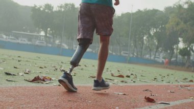 Koşu pistinde protez bacakla koşan engelli bir sporcu. Motivasyonel ampütasyon atleti koşucusu