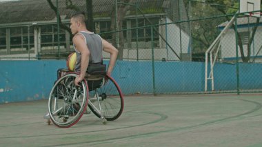 Dışarıda basketbol sahasında tekerlekli sandalyedeki felçli bir basketbolcu. Engelli sporu ve sakatlık konsepti