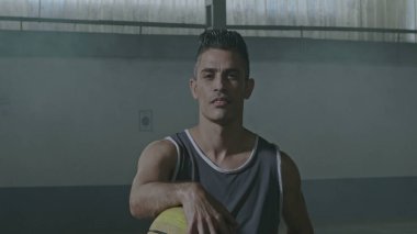 Tekerlekli sandalyede top tutan bir İspanyol engelli basketbolcu. Engelli ve belden aşağısı felçli bir sporcunun portresi. Spor ve kararlılık kavramı