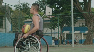 Dışarıda basketbol sahasında tekerlekli sandalyedeki felçli bir basketbolcu. Engelli sporu ve sakatlık konsepti