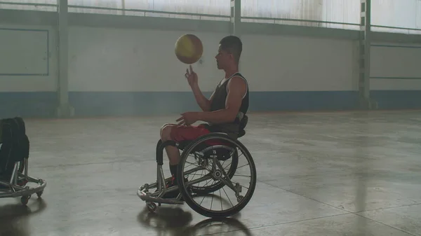 Two paraplegic athletes on wheelchair. A disabled athlete spinning ball with hand