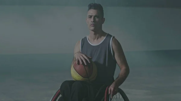 One hispanic disabled basketball player athlete on wheelchair holding ball. Portrait of a latin paraplegic sportive person with disability. Sport and determination concept