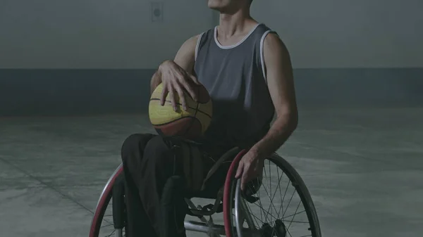 One hispanic disabled basketball player athlete on wheelchair holding ball. Portrait of a latin paraplegic sportive person with disability. Sport and determination concept