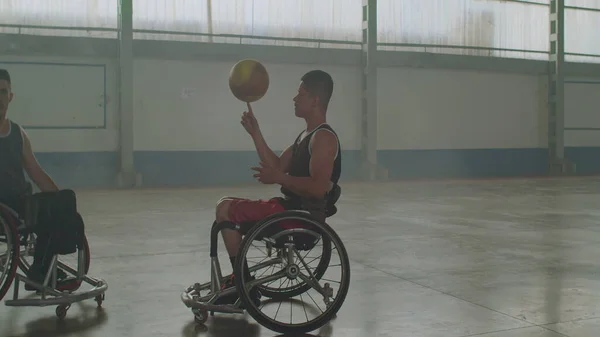 Two paraplegic athletes on wheelchair. A disabled athlete spinning ball with hand