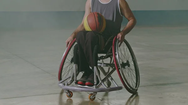 One hispanic disabled basketball player athlete on wheelchair holding ball. Portrait of a latin paraplegic sportive person with disability. Sport and determination concept