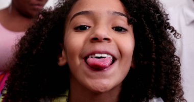 Dilini dışarı çıkaran çeşitli küçük bir kız.