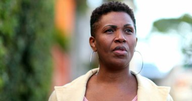 Ciddi bir Afrikalı kadın sokakta kameraya doğru yürüyor.