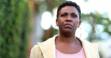 Ciddi bir Afrikalı kadın sokakta kameraya doğru yürüyor.