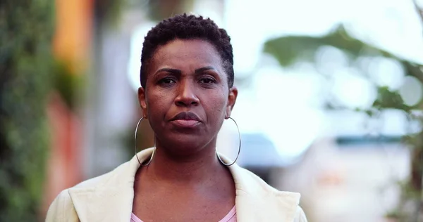 Ciddi bir Afrikalı kadın sokakta kameraya doğru yürüyor.