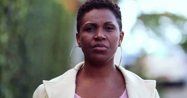 Ciddi bir Afrikalı kadın sokakta kameraya doğru yürüyor.