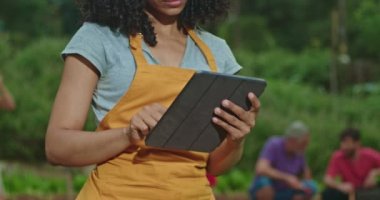 One black woman farmer using tablet device at agriculture farm. Person inspecting food business with modern technology