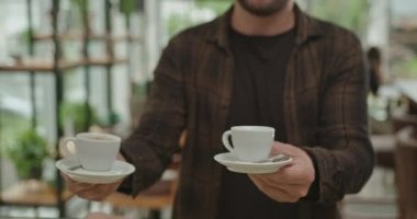 Genç adam kafe reyonunda ekspresso alıyor. Müşteri küçük işletmelerden kahve alıyor ve arkadaşıyla masaya oturuyor. Kahve dükkanının içi..