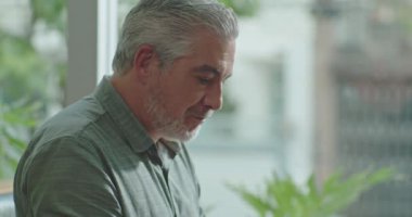 Laptop bilgisayarının önünde internette gezinen yaşlı iş adamının profili. Daha yaşlı bir girişimciye odaklanmış