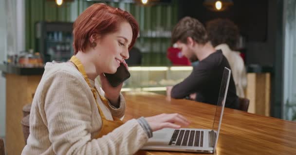 Coffee Shop Female Staff Speaking Phone Looking Laptop Computer Happy — Vídeo de Stock