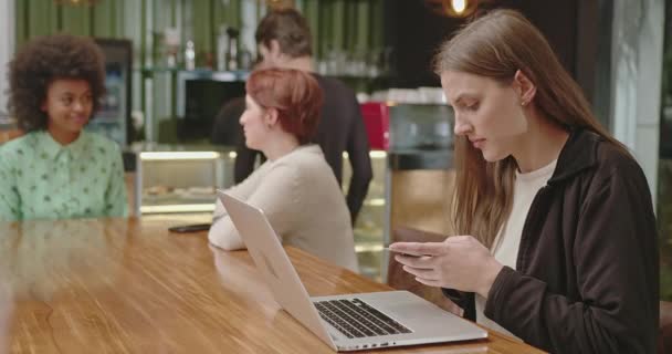 Happy Young Woman Picks Phone Sitting Coffee Shop Using Laptop — Vídeos de Stock