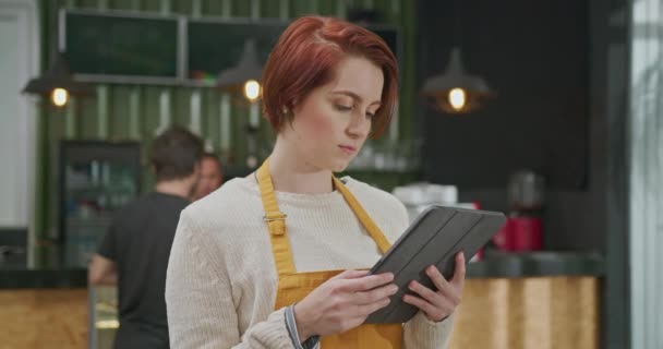 Mujer Joven Empleada Usando Delantal Pie Dentro Cafetería Sosteniendo Dispositivo — Vídeos de Stock