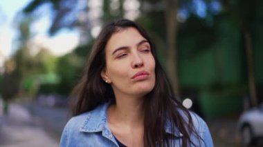 Düşünceli bir kadın dışarı çıkıp düşünüyor. Yakından bakınca insan yüzü düşüncelere dalmış yürüyor.