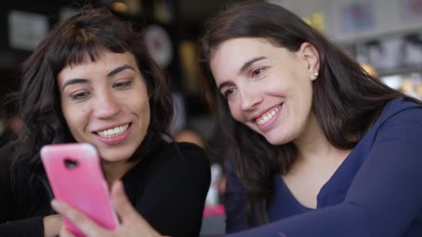 Dos Mujeres Jóvenes Mirando Pantalla Del Dispositivo Teléfono Inteligente Sonriendo — Vídeos de Stock
