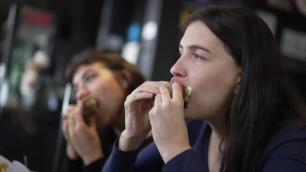 Two Young Women Eating Hamburgers People Restaurant Taking Bite Burgers — Vídeos de Stock