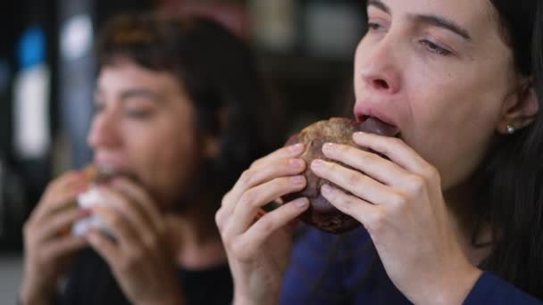 Zwei Menschen Essen Burger Junge Frauen Nehmen Einen Bissen Cheeseburger — Stockvideo