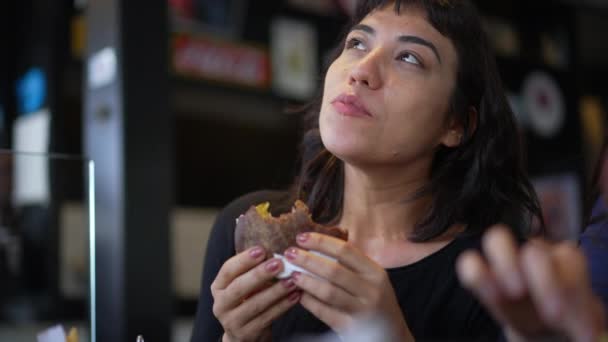 Одна Задумчивая Латиноамериканка Ест Бургер Бразилец Ест Чизбургер Ресторане Обед — стоковое видео