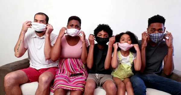 Family putting covid face mask together, interracial parents and children wearing preventive mask