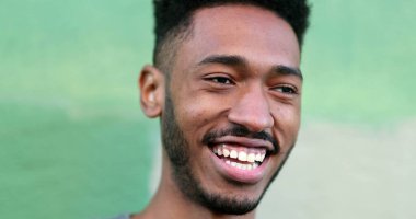 Mutlu genç siyah adam gülüyor ve gülümsüyor. Afrika kökenli gerçek hayat gülüyor ve gülümsüyor